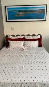 ein Bett mit gepunkteter Bettwäsche und ein Bild an der Wand in der Unterkunft Studio Beira Mar in Imbituba
