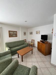 a living room with green couches and a tv at Appartamento Fontane in Panchia