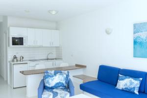 a living room with a blue couch and a kitchen at Apartamentos Orly Club Arena Dorada in Puerto del Carmen