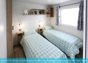 two beds in a small room with a window at Siblu Camping in de Bongerd in Oostkapelle +25 photos