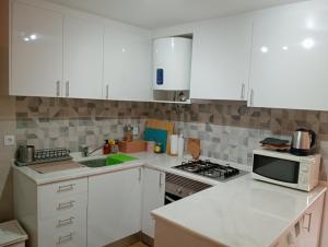 a kitchen with white cabinets and a sink and a microwave at Casa Nossa in Lisbon