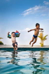 two young boys jumping into a swimming pool at Le Kroma Villa in Phumĭ Pr&ecirc;k