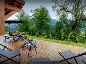 een houten terras met stoelen en een tafel met een parasol bij Chalet Lezopau - OVO Network in Samoëns