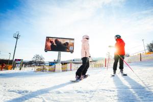 two people on skis in the snow in front of a screen at Hotel Monínec - Depandance Nová Javorka in Moninec +61 photos