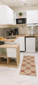 a kitchen with white cabinets and a sink and a rug at superbe appartement et son garage privé gratuit in Nîmes