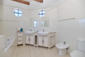 een witte badkamer met 2 wastafels en een toilet bij Blombossie in Arniston