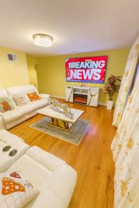 Sleeps 4 Guests Near Yale & Downtown - Free Parking في نيو هافن: غرفة معيشة مزودة بشاشة كبيرة تعرض أخباراً عاجلة