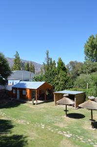 a building with two straw umbrellas in the grass at Gosén Cabañas Sanagasta in Villa Bustos