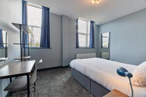 a bedroom with a bed and a desk and windows at Apartment Stays in Newcastle upon Tyne