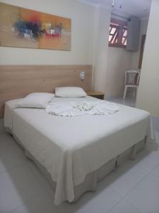 Pousada Eco Da Montanha في باسا كواترو: غرفة نوم بسرير كبير مع ملاءات بيضاء