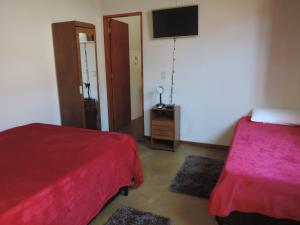 a bedroom with two beds and a flat screen tv at Pousada Melhor Hora in Cunha