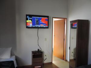 a flat screen tv on the wall of a bedroom at Pousada Melhor Hora in Cunha