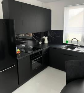 eine Küche mit schwarzen Schränken und einer Spüle in der Unterkunft Łagowski Zakątek z Sauną in Łagów