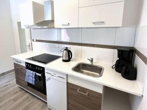 a white kitchen with a sink and a stove at Gemütliche Apartments in Herten in Herten +18 photos