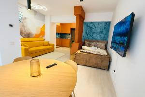 een woonkamer met een tafel en een gele bank bij Smart Serendipity Apartments in Boekarest