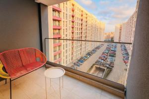 een balkon met een rode stoel en uitzicht op een parkeerplaats bij Smart Serendipity Apartments in Boekarest