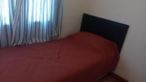 a bedroom with a red bed and a window at Departamento 1 in Comodoro Rivadavia