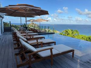 Saint BarthelemyにあるThe Red Cloud Villa with Incredible Ocean View !!!!のプール(椅子、パラソル付)