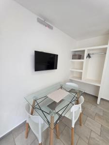 ピラルにあるAparts Magallanesのガラスのテーブル、白い椅子2脚、テレビ