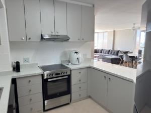 una cucina con mobili bianchi e un forno a piano cottura di Odeon Ocean View a Strand