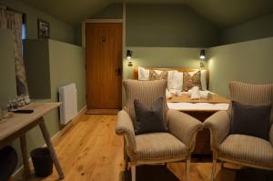 a bedroom with a bed with two chairs and a table at The Hollow Bottom in Guiting Power