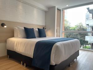 a bedroom with a large bed with a large window at Nova Iorque Suites by Avia Suites in Bogotá