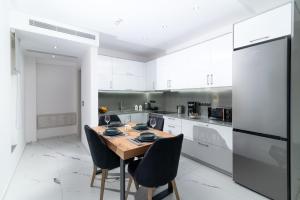 a kitchen with white cabinets and a wooden table and chairs at Villa Melora in Pitsidia
