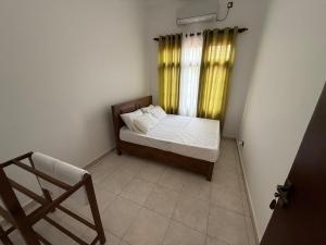 a small bedroom with a bed and a yellow curtain at Ceylon Villa in Matara