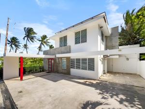 Casa blanca con puerta roja y palmeras en Villa Capitán Modern Stay Near Beach with pool, en Vega Alta