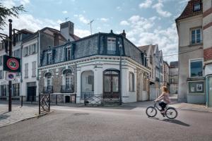 Le Secret d'Alice Centre ville Balcon في لاني: امرأة تركب دراجة أمام مبنى