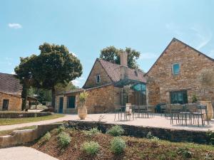 an external view of a stone house with tables and chairs at Domaine St-Amand in Saint-Amand-de-Coly