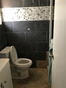 a bathroom with a toilet and a black tiled wall at PalmBeachDowntownPrivatHouseShare99perpersonupto5Party in West Palm Beach +43 photos