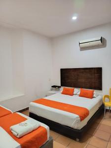 two beds in a room with orange and white at hotel san nicolas colonial in Barranquilla
