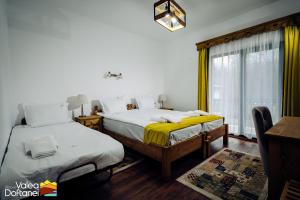 a bedroom with two beds and a window at Mai cu Mot Doftana Luxury Chalets in Trăisteni
