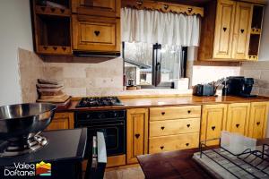 a kitchen with wooden cabinets and a stove top oven at Mai cu Mot Doftana Luxury Chalets in Trăisteni