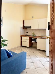 een keuken met witte kasten en een blauwe bank bij Holihome Vascello A7 in Tortoreto Lido