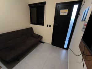 Centro comercial João Batista Julião في غوارويا: غرفة معيشة مع أريكة وباب أسود