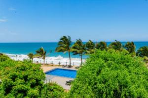 a swimming pool next to the beach with palm trees at Peacock Beach Resort- Hambantota in Hambantota