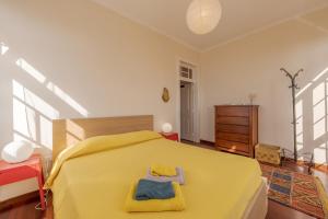 a bedroom with a yellow bed with two towels on it at Flora Garden House by HR Madeira in Estreito da Calheta