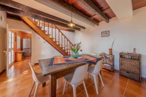 a dining room with a wooden table and white chairs at Flora Garden House by HR Madeira in Estreito da Calheta
