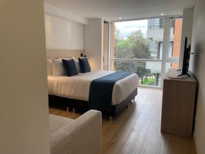 a bedroom with a bed and a tv and a window at Nova Iorque Suites by Avia Suites in Bogotá