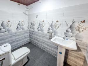 a bathroom with a toilet and a sink and vases on the wall at White Rose Holiday Resort in Anuradhapura