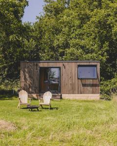 Una pequeña cabaña con dos sillas y un televisor en un campo. en Parcel Tiny House I Richecourt vue Prairie, en Mesbrecourt-Richecourt
