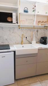 a kitchen with a sink and a microwave at cocon des arènes et parking in Nîmes