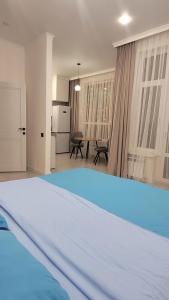 a bedroom with a bed and a kitchen and a table at Однокомнатная квартира посуточно in Astana