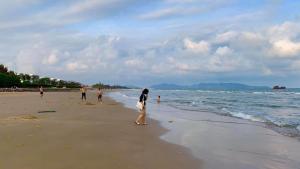 a woman walking on a beach near the water at Hà Giang Homestay - Nhà phố Du lịch Biển Vũng Tàu Gần bãi biển Long cung in Vung Tau
