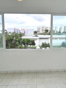 an empty room with a view of a city from a window at La Varangue bleu T3 Aéroport Sainte Marie in Sainte-Marie