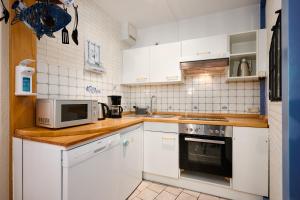 een keuken met witte kasten, een fornuis en een magnetron bij Deichweg 33 Käptns Kajüte in Kalifornien