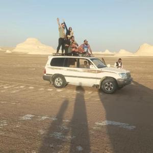 un grupo de personas de pie en el techo de un vehículo en el desierto en Tours of the White Desert, en Az Zabū