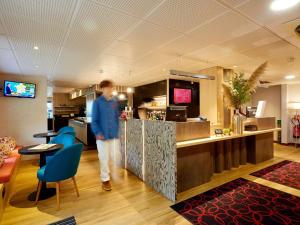 Un hombre de pie en una barra de un restaurante. en ibis Le Mans Est Pontlieue, en Le Mans